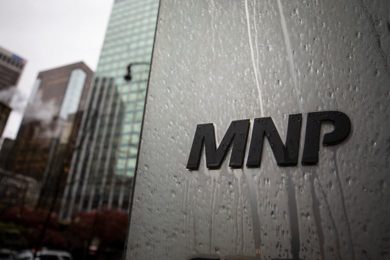 A picture of an office building with the words 'MNP' on it during a rainy day.