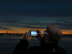 Families and friends take in the eclipse at Crysler's Farm outside Cornwall Monday. A man takes some photos while it's dark.