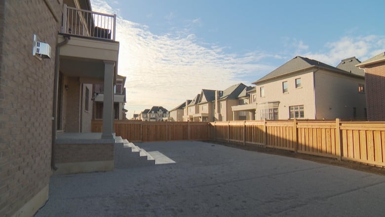 The backyard of a residential home with gravel on the ground and a set of concrete stairs.