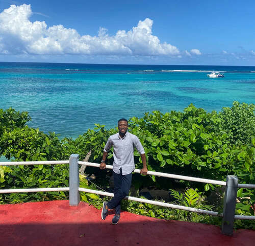 Runako Gentles leaning against a fence overlooking the ocean