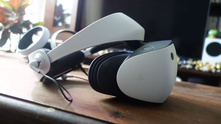 A side view of the PlayStation VR2, which sits on a wood table.