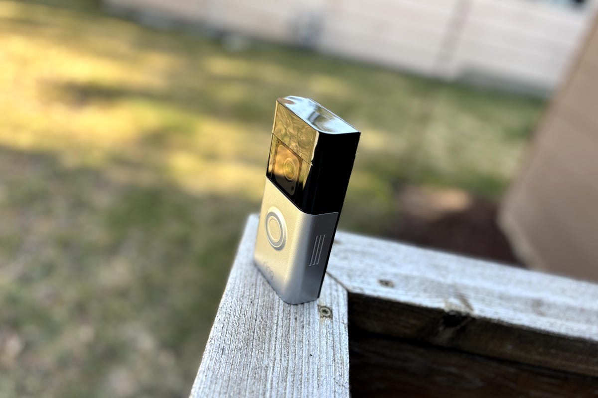 A Ring Battery Doorbell Pro sits on top of porch fencing waiting for installation.