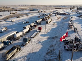 A truck convoy of anti-COVID-19 vaccine mandate demonstrators block the highway at the busy U.S. border crossing in Coutts, Alta., Wednesday, Feb. 2, 2022. Opening arguments are scheduled today in the trial for three men charged for their role in the blockade of the Canada-U.S. border at Coutts, Alta.