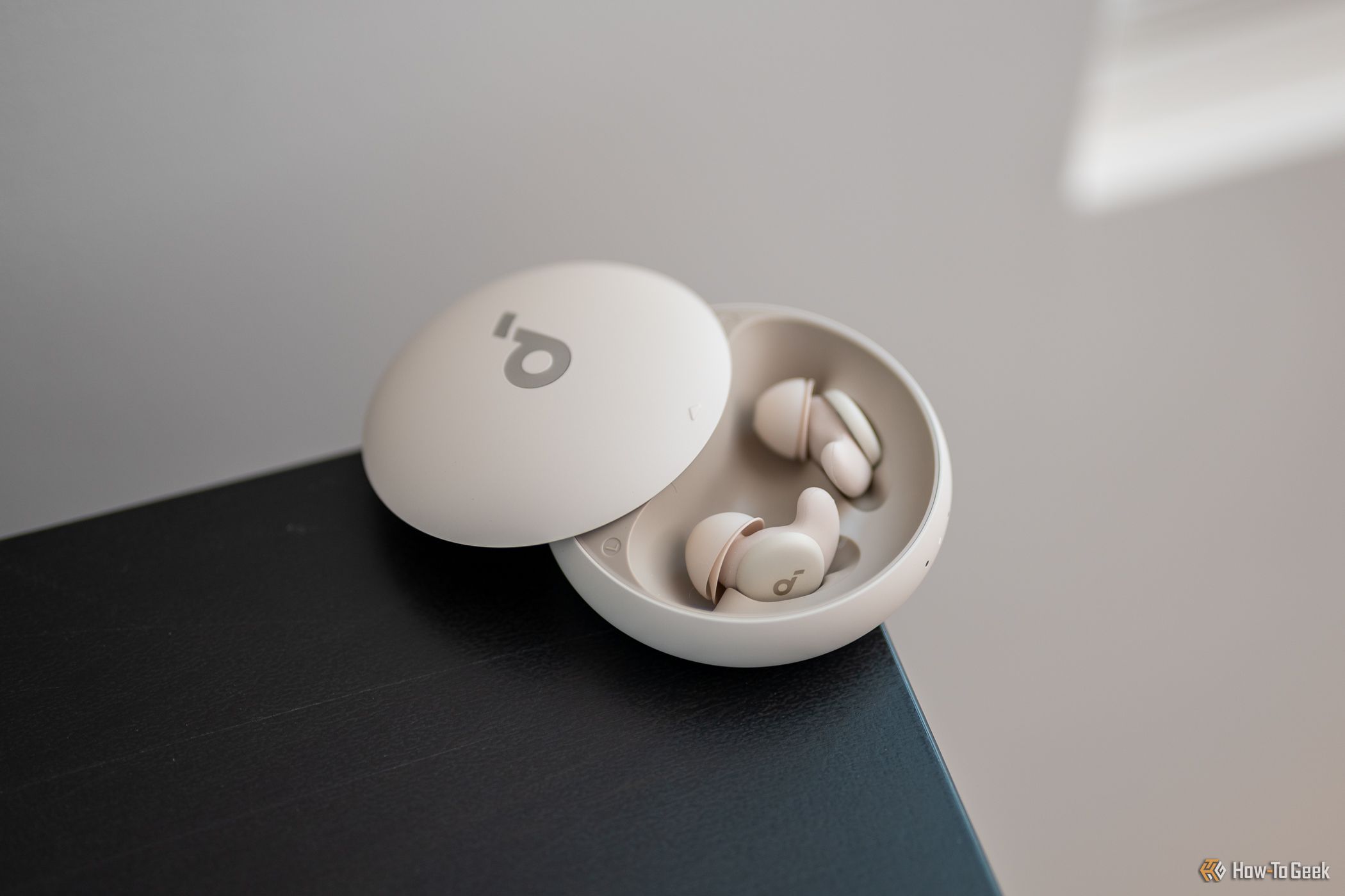 Soundcore Sleep A20 Bluetooth Earbuds in its charging case sitting on a table
