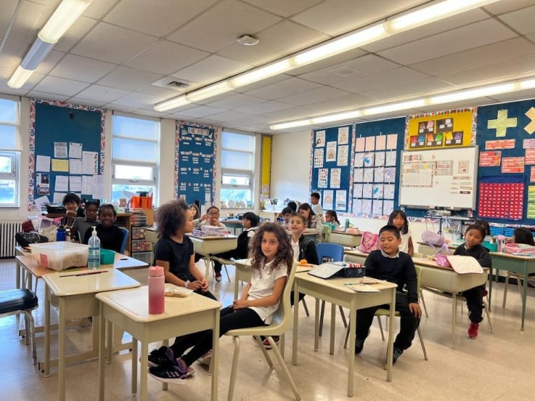 A class full of young students sit at their desks.