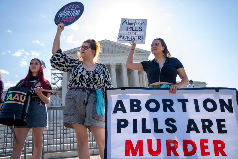 Anti-abortion protesters hold up signs while demonstrating outside the U.S. Supreme Court.