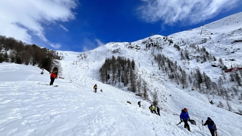 Skiers are seen on a snowy mountain.