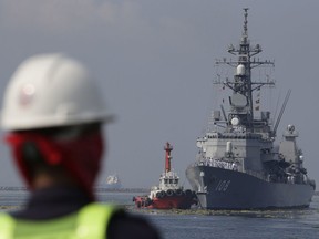 FILE - A Filipino port worker looks as the Japanese Ship Akebono (DD-108), a Murasame-class destroyer of the Japan Maritime Self-Defense Force, prepares to dock for a goodwill visit at Manila's south harbor, Philippines on Sept. 27, 2018. The United States, Japan, Australia and the Philippines will hold their first joint naval exercises, including anti-submarine warfare training, in a show of force Sunday, April 7, 2024 in the South China Sea where Beijing's aggressive actions to assert its territorial claims have caused alarm.