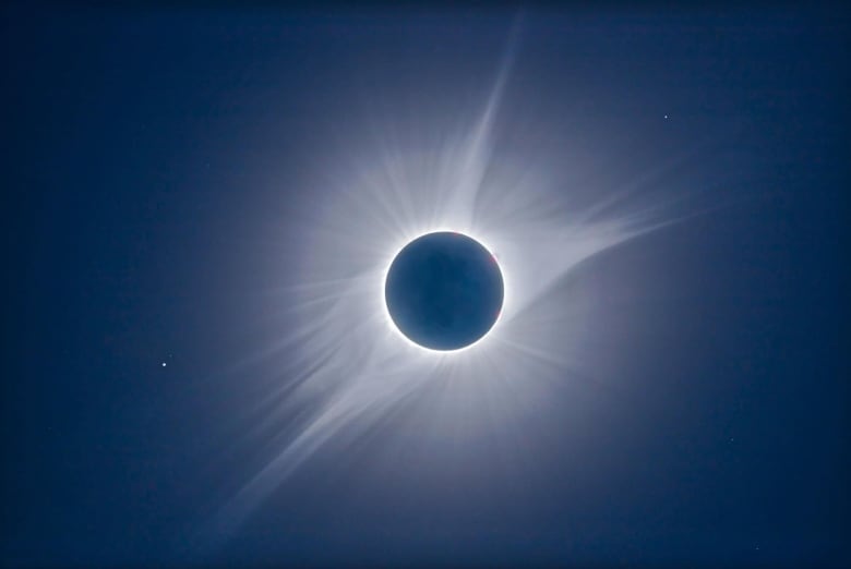 White streamers emanate from a black disk.