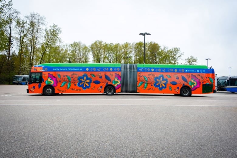 A long Translink bus is pictured colorfully decorated on the outside with painted flowers and plants. 