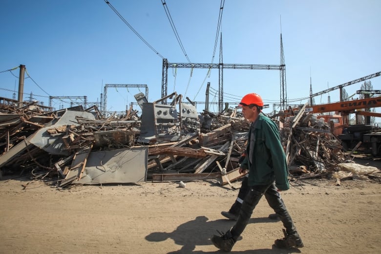 An employee of a critical power infrastructure installation, which was recently hit during Russia's missile strike, walks by its destroyed part, amid Russia's attack on Ukraine, in Kharkiv, Ukraine, April 10, 2024. 