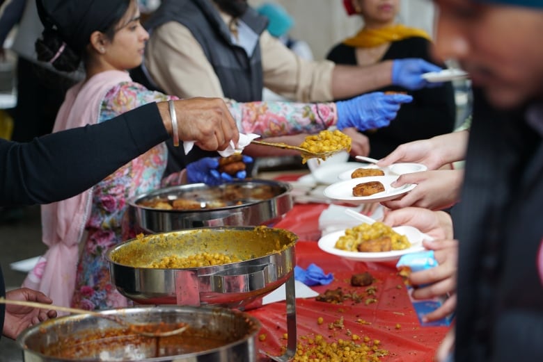 People serve food in a line.