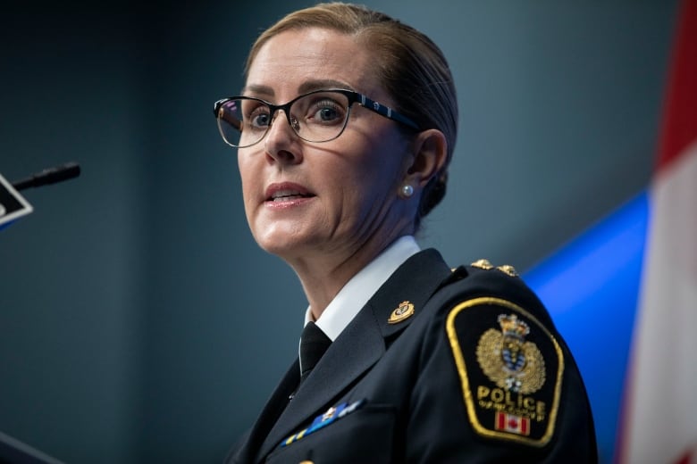 A white woman wearing a police uniform looks at the camera.