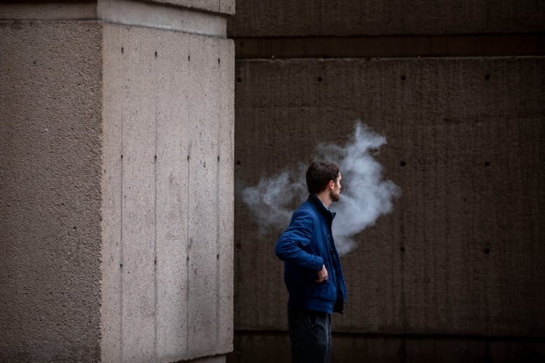 A man exhales vapor while using a vape pen in Vancouver.