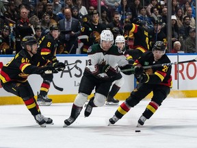 Vancouver Canucks' Elias Pettersson (40), Nils Hoglander (21), and Arizona Coyotes' Matias Maccelli (63) vie for the puck during the second period of an NHL hockey game in Vancouver, on Wednesday, April 10, 2024.