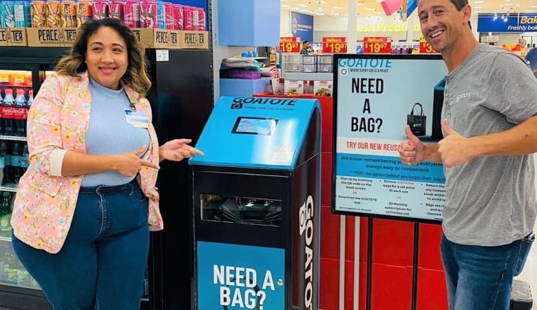 Two Walmart employees stand next to a kiosk here customers could, for a fee, get a resuable bag.