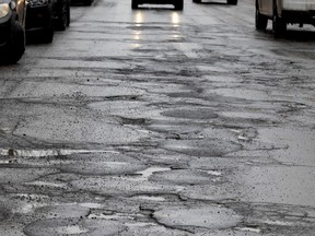 Headlights shine on a road full of potholes