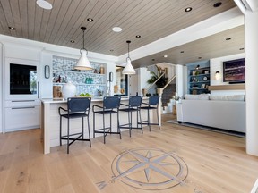 The kitchen features built-in appliances, a moonstone fan backsplash, Caesarstone quartz bar countertops in Cloudburst, pendant lights by Hinkley and a custom floor design.