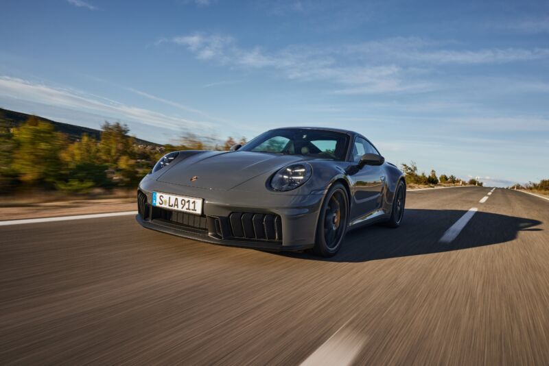 A grey Porsche 911 drives on a road