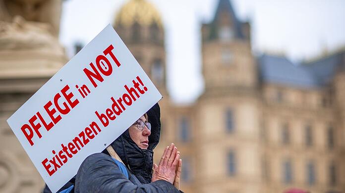 Bei einer Protestaktion vor dem Schweriner Landtag hält eine Teilnehmerin ein Schild mit der Aufschrift "Pflege in Not - Existenzen bedroht!".