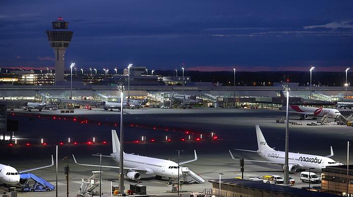 Flugzeuge stehen vor Sonnenaufgang auf dem Flughafen Franz-Josef-Strauß.