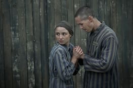 Jonah Hauer-King as Lali Sokolov seen here walking through Auschwitz with German-born actor Jonas Nay as Nazi officer Stefan Baretzki, front right