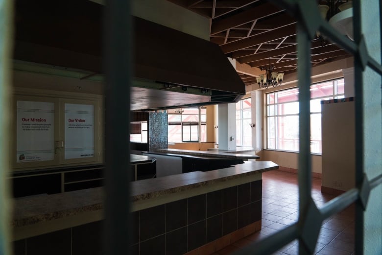 an empty room behind a barred off cage-style fence.