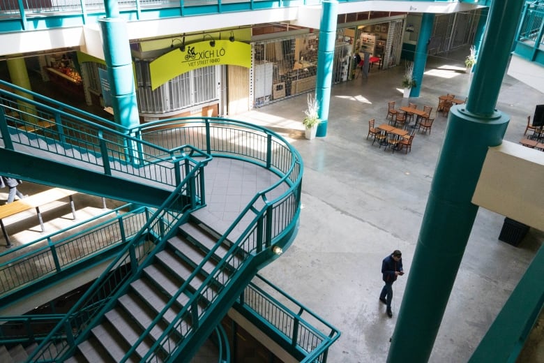 a photo of an empty mall, businesses are shuttered, one person walks in the large open space.