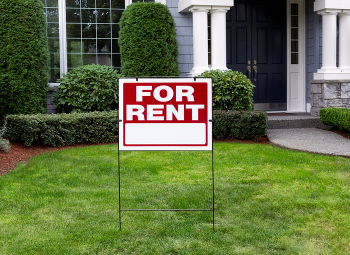 A house with a for rent sign in front of it.