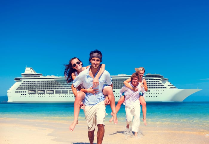 Four people having fun on the beach with a cruise ship in the water behind them.