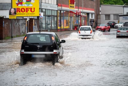 Saarland, Saarbrücken: Autofahrer fahren trotz der Überschwemmungen in der Fischbachstraße durch die steigenden Fluten.