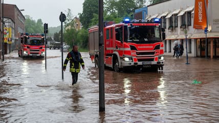 Feuerwehrleute bewegen sich und ihre LKW durch das Hochwasser in der Fischbachstrasse in Saarbrücken.