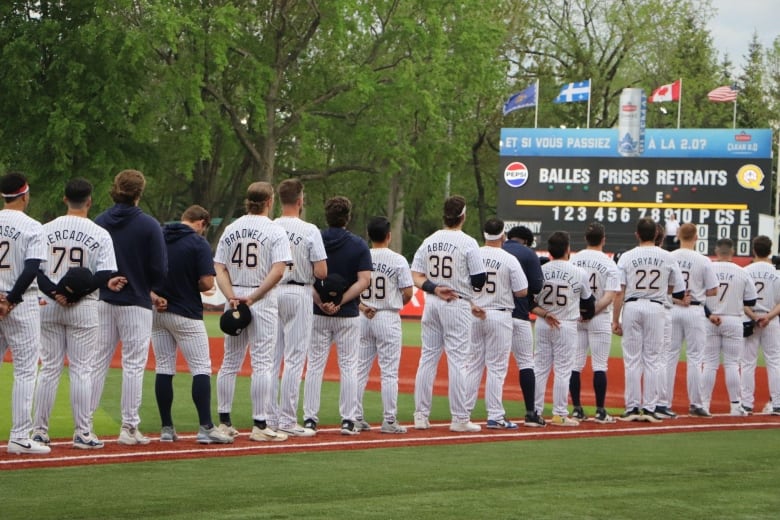 Baseball players stand in a row at on a baseball field