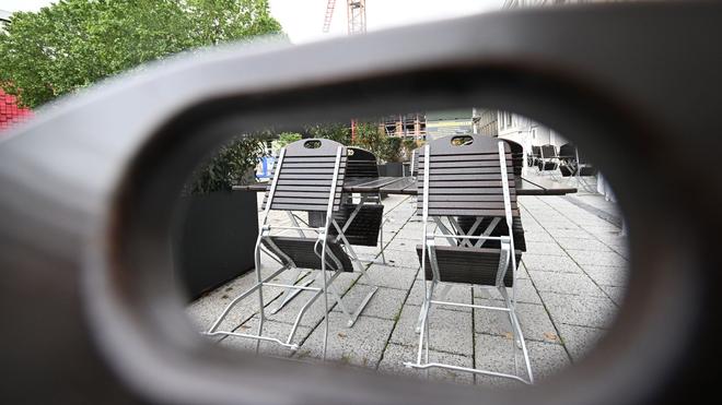 Wochenende: Stühle in einer Außengastronomie sind bei regnerischem Wetter hochgeklappt.