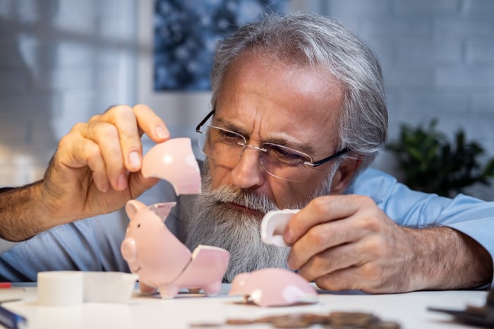 A person examining the pieces of a broken piggy bank.