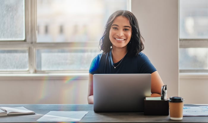 A smiling person at a laptop.