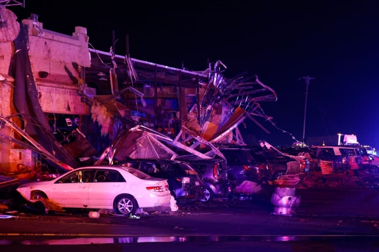 Cars have debris on top of them near a gas station that was severely damaged after a suspected tornado.