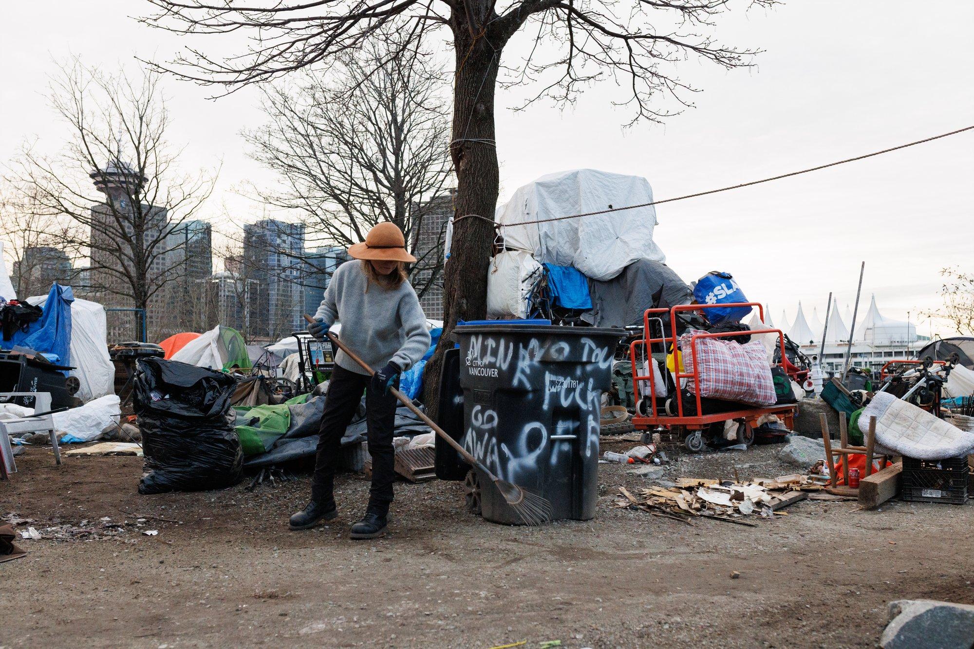 An encampment resident who identifies herself as âTâ sweeps up garbage at CRAB Park in February. Along with cleanups, residents participate in regular safety patrols and other activities to keep order at the park.