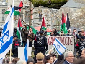 Police officers stand between groups carrying Israeli and Palestinian flags