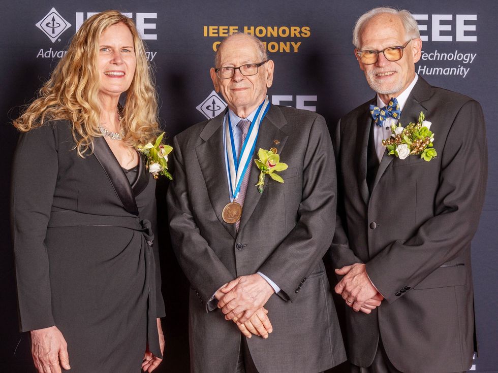 group of 3 people standing for a portrait, middle person with a medal around their neck