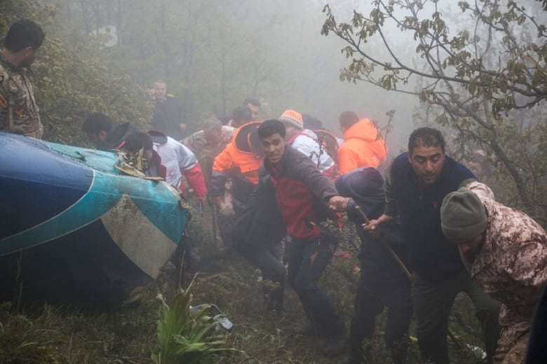 Rescue team members work at the crash site of a helicopter. 