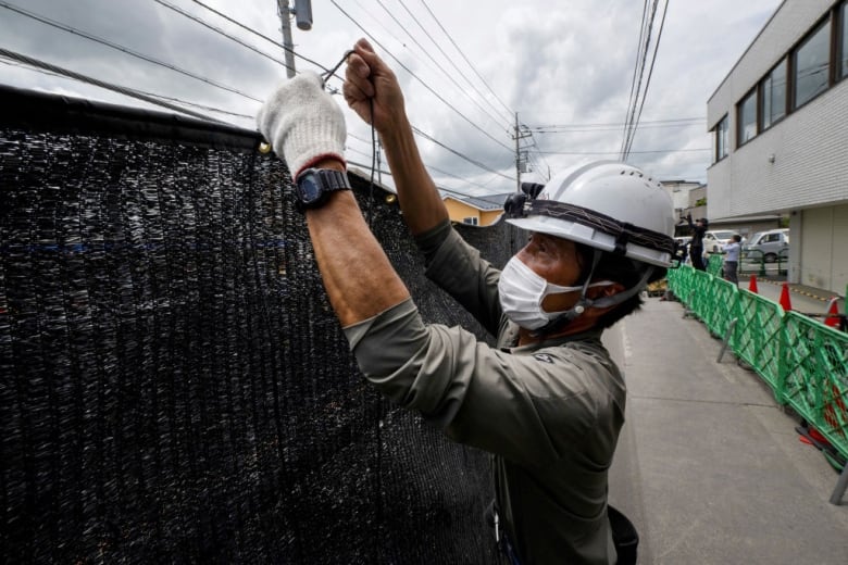 A worker installs a barrier to block the sight of Japan's Mount Fuji.