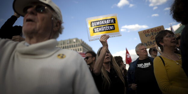 Eine Person in einer Menschenmenge hält ein Schild mit der Aufschrift 