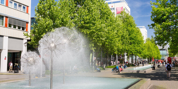 Eine Fußgängerzone mit Springbrunnen, Bänken und Bäumen