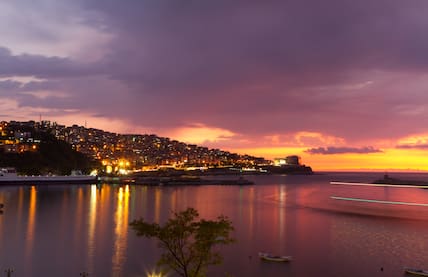 Sonnenuntergang hinter der türkischen Stadt Zonguldak am Schwerzen Meer, deren Lichter sich im Meer spiegeln