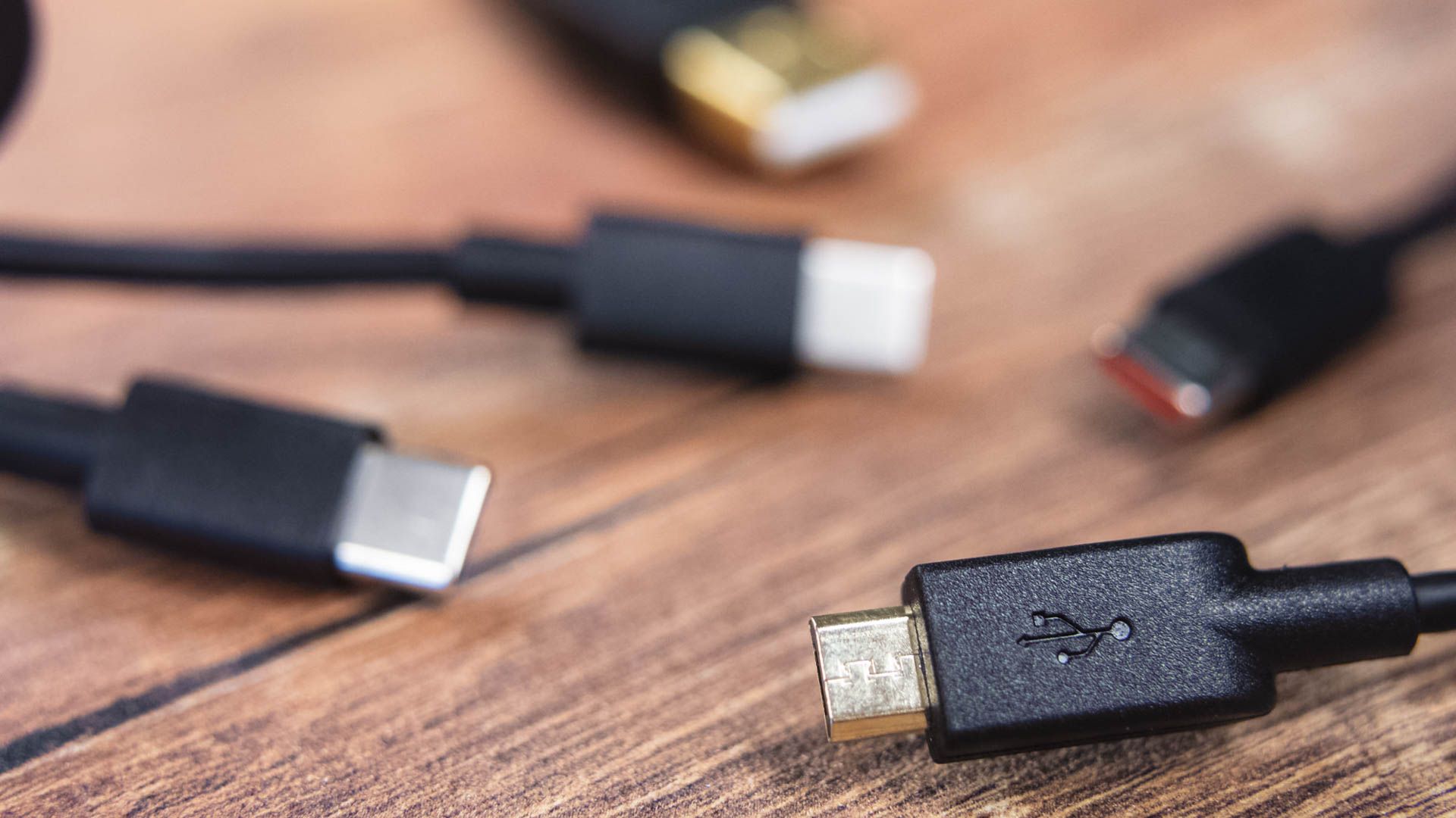 Various USB cable connectors on a wood grain surface.