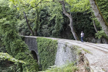 Wanderer auf einer Brücke an einer alten Bahnlinie, die durch Wald führt, auf der Pilion-Halbinsel