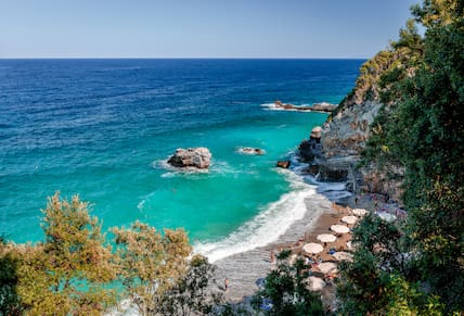 Blick von oben auf den Mylopotamos Strand auf der Pilion-Halbinsel, umgeben von Klippen und mit türkis-blauem Meer davor