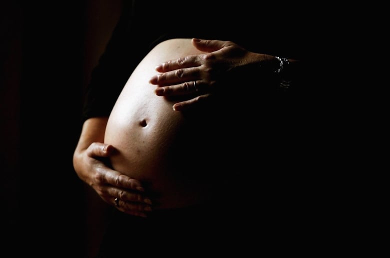 Hands on the belly of an expectant mother.