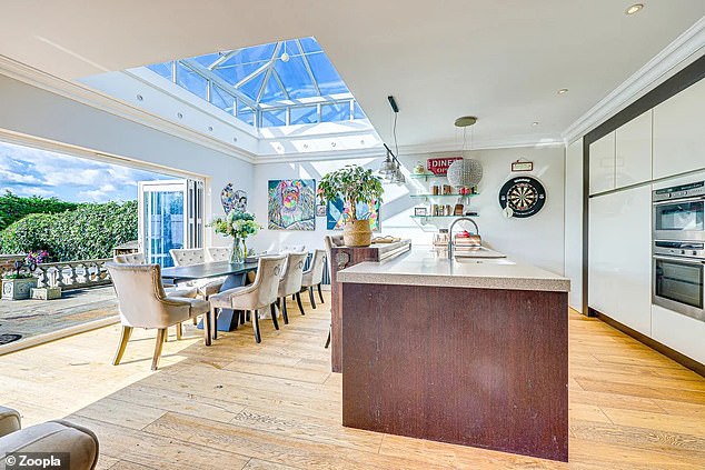 The large open-plan living room houses a modern kitchen with an island and dining area